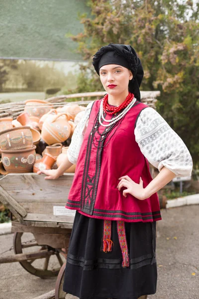 Menina bonita em vestido nacional. Segurando um pote antigo em suas mãos. Roupas antigas do final do século XIX. Belo vestido e saia em uma mulher. O conceito de vida rural, tradições nacionais — Fotografia de Stock