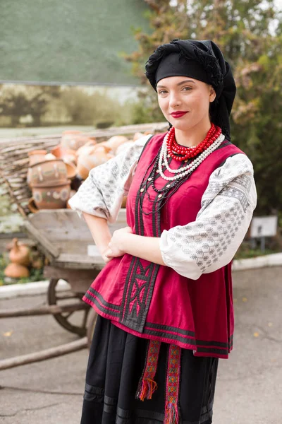 Hermosa chica en vestido nacional. Llevando una olla antigua en sus manos. Ropa antigua de finales del siglo XIX. Hermoso vestido y falda en una mujer. El concepto de vida rural, tradiciones nacionales — Foto de Stock