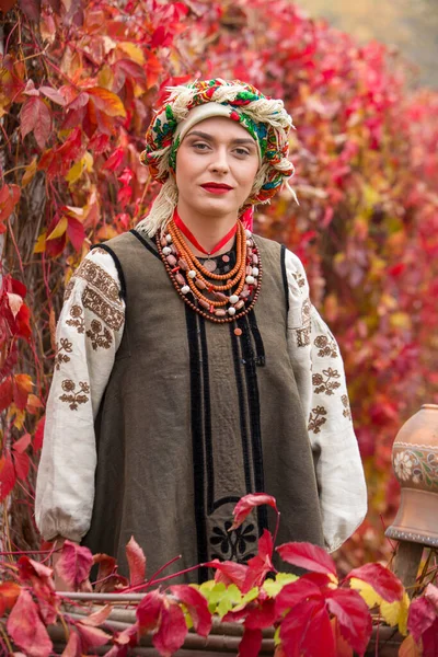 Bella ragazza in abito nazionale. Con un'antica pentola di argilla. Abbigliamento antico della fine del XIX secolo. Bellissimo vestito e gonna su una donna. Bellissimo autunno e foglie. Abbigliamento della fine del XIX secolo — Foto Stock