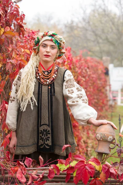 Krásná dívka v národních šatech. Se starobylým hliněným hrncem. Starožitné oblečení z konce 19. století. Krásné šaty a sukně na ženě. Krásný podzim a listí. Oblečení z konce 19. století — Stock fotografie