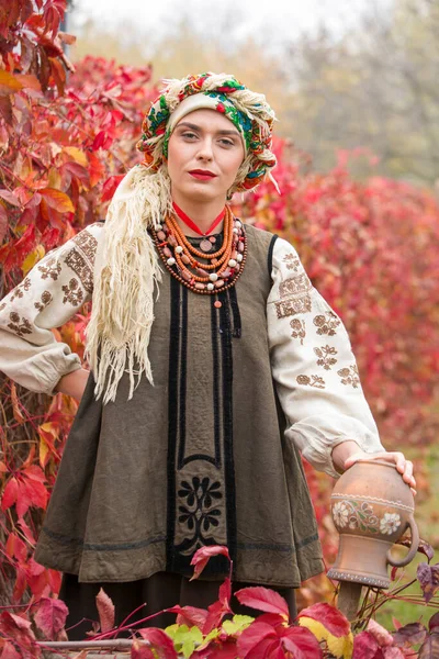 Krásná dívka v národních šatech. Se starobylým hliněným hrncem. Starožitné oblečení z konce 19. století. Krásné šaty a sukně na ženě. Krásný podzim a listí. Oblečení z konce 19. století — Stock fotografie