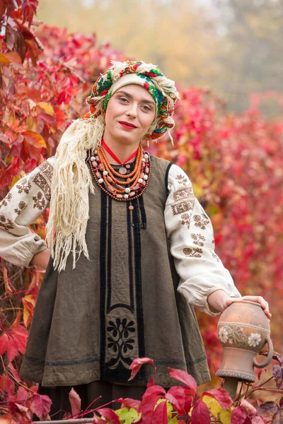 民族衣装の美しい女の子。古代の粘土鍋で。19世紀後半のアンティークの服。女性の美しいドレスやスカート。美しい秋と葉。19世紀後半の衣服 — ストック写真