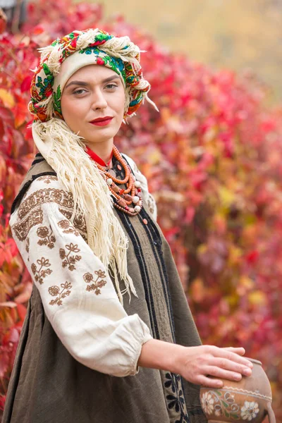 Gyönyörű lány nemzeti ruhában. Egy ősi agyagcseréppel. A 19. század végi antik ruhák. Gyönyörű ruha és szoknya egy nőn. Gyönyörű ősz és levelek. Ruházat a 19. század végén — Stock Fotó