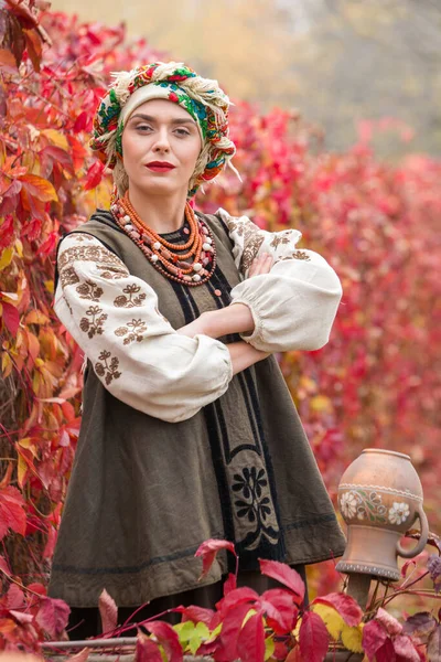 Gyönyörű lány nemzeti ruhában. Egy ősi agyagcseréppel. A 19. század végi antik ruhák. Gyönyörű ruha és szoknya egy nőn. Gyönyörű ősz és levelek. Ruházat a 19. század végén — Stock Fotó