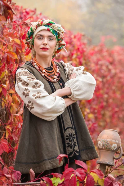 Schöne Mädchen in Nationalkleidung. Mit einem alten Tontopf. Antike Kleidung aus dem späten 19. Jahrhundert. Schönes Kleid und Rock auf eine Frau. Schöner Herbst und Blätter. Kleidung des späten 19. Jahrhunderts — Stockfoto