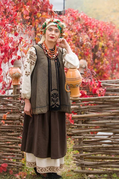 Schöne Mädchen in Nationalkleidung. Mit einem alten Tontopf. Antike Kleidung aus dem späten 19. Jahrhundert. Schönes Kleid und Rock auf eine Frau. Schöner Herbst und Blätter. Kleidung des späten 19. Jahrhunderts — Stockfoto