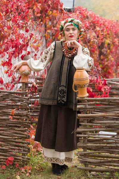Beautiful girl in national dress. With an ancient clay pot. Antique clothing of the late 19th century. Beautiful dress and skirt on a woman. Beautiful autumn and leaves. Clothing of the late 19th — Stock Photo, Image