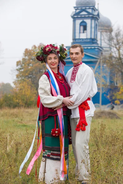 Fille et gars en costumes rétro dans la rue dans le vieux village. Mise en scène rétro d'un rite ancien. Belle couronne sur une fille. Le mec embrasse la fille, les deux sourient. Vêtements anciens de la fin — Photo