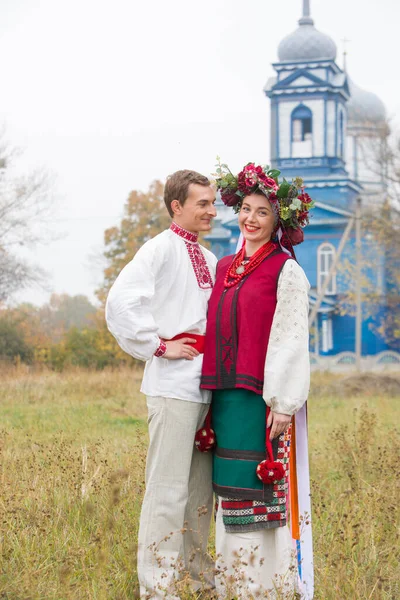 Fille et gars en costumes rétro dans la rue dans le vieux village. Mise en scène rétro d'un rite ancien. Belle couronne sur une fille. Le mec embrasse la fille, les deux sourient. Vêtements anciens de la fin — Photo