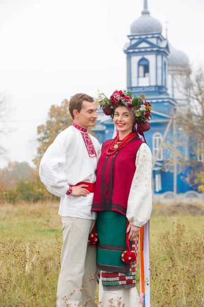 Fille et gars en costumes rétro dans la rue dans le vieux village. Mise en scène rétro d'un rite ancien. Belle couronne sur une fille. Le mec embrasse la fille, les deux sourient. Vêtements anciens de la fin — Photo