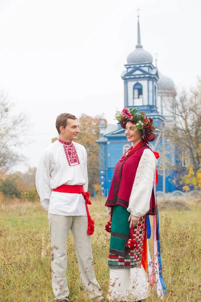 Fille et gars en costumes rétro dans la rue dans le vieux village. Mise en scène rétro d'un rite ancien. Belle couronne sur une fille. Le mec embrasse la fille, les deux sourient. Vêtements anciens de la fin — Photo