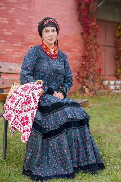 Vrouw met een mand in retro kleding uit de 19e eeuw. Antieke kleding uit de late 19e eeuw. Mooie jurk en rok aan een vrouw. Kralen en decoratie op een meisje. Oude plaats. Traditie en — Stockfoto