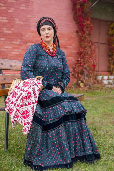 Donna con cesto in abiti retrò del XIX secolo. Abbigliamento antico della fine del XIX secolo. Bellissimo vestito e gonna su una donna. Perline e decorazioni su una ragazza. Un posto antico. Tradizione e — Foto Stock