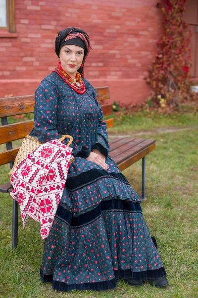 Frau mit Korb in Retro-Kleidung aus dem 19. Jahrhundert. Antike Kleidung aus dem späten 19. Jahrhundert. Schönes Kleid und Rock auf eine Frau. Perlen und Dekoration auf einem Mädchen. Antiker Ort. Tradition und — Stockfoto