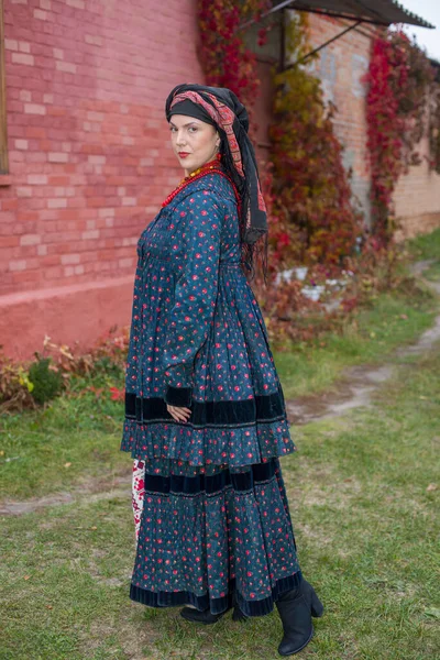 Mulher com uma cesta em roupas retrô do século XIX. Roupas antigas do final do século XIX. Belo vestido e saia em uma mulher. Grânulos e decoração em uma menina. Um lugar antigo. Tradição e — Fotografia de Stock