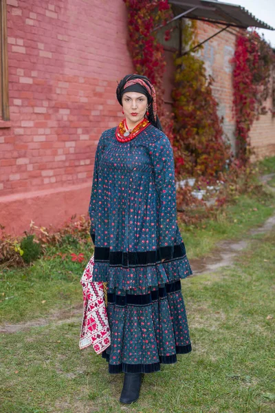 Mulher com uma cesta em roupas retrô do século XIX. Roupas antigas do final do século XIX. Belo vestido e saia em uma mulher. Grânulos e decoração em uma menina. Um lugar antigo. Tradição e — Fotografia de Stock