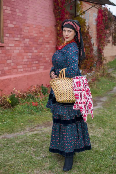 Vrouw met een mand in retro kleding uit de 19e eeuw. Antieke kleding uit de late 19e eeuw. Mooie jurk en rok aan een vrouw. Kralen en decoratie op een meisje. Oude plaats. Traditie en — Stockfoto