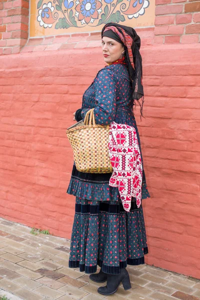 Woman with a basket in retro clothes of the 19th century. Antique clothing of the late 19th century. Beautiful dress and skirt on a woman. Beads and decoration on a girl. Ancient place. Tradition and — Stock Photo, Image