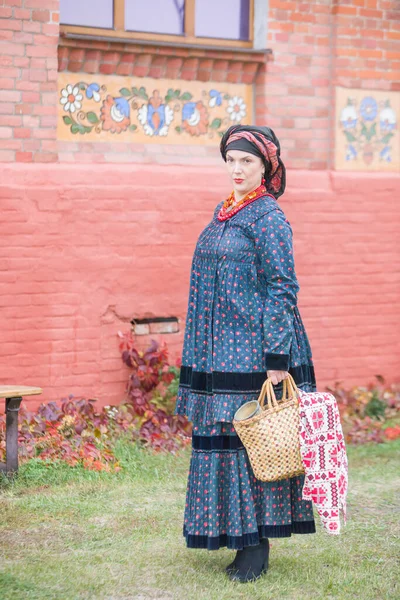Woman with a basket in retro clothes of the 19th century. Antique clothing of the late 19th century. Beautiful dress and skirt on a woman. Beads and decoration on a girl. Ancient place. Tradition and — Stock Photo, Image