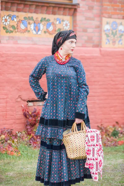 Woman with a basket in retro clothes of the 19th century. Antique clothing of the late 19th century. Beautiful dress and skirt on a woman. Beads and decoration on a girl. Ancient place. Tradition and — Stock Photo, Image