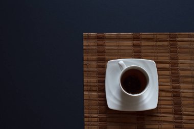 Tablo üzerinde koyu mavi zemin üzerine üstten görünüm beyaz fincan çay. Soyut mutfak arka plan.