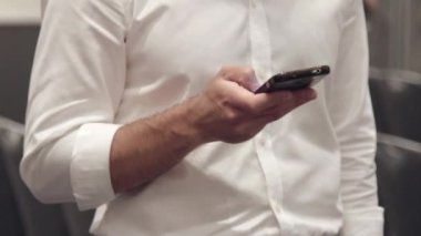 Beyaz gömlekli bir adam bir şey telefonuna yazarak