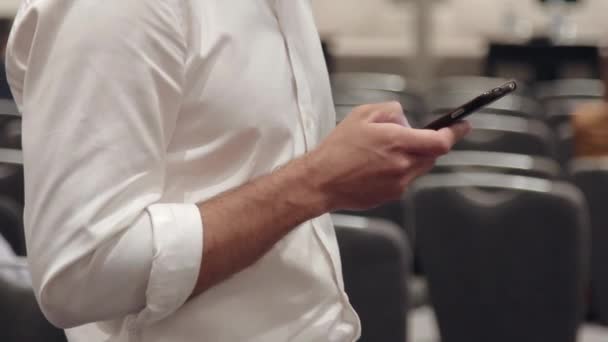 Egy férfi egy fehér inget gépelés valamit a telefon — Stock videók