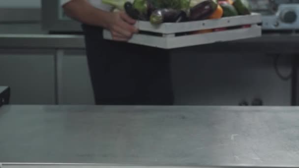Повар кладет коробку с овощами, зеленью и грибами на стол — стоковое видео