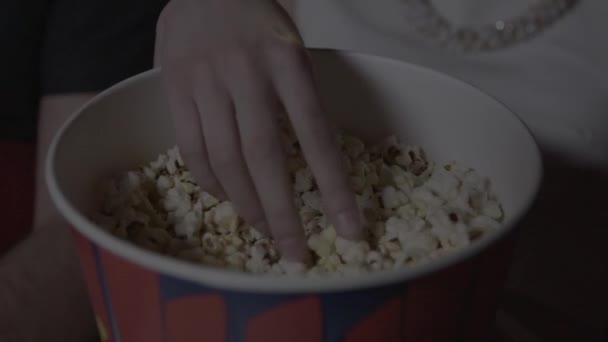 Manos toma las palomitas de maíz de un vaso de papel en el cine — Vídeo de stock