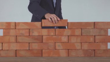 Adam tuğla duvara koyar.