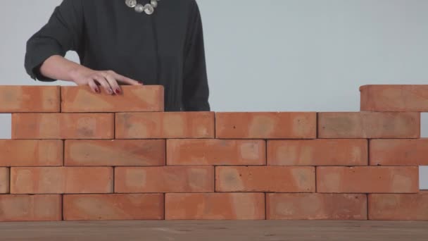 Woman puts a brick in the wall — Stock Video