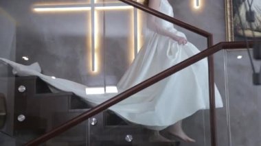 Çıplak ayaklı zarif bayan elinde trenle merdivenlerden iniyor.