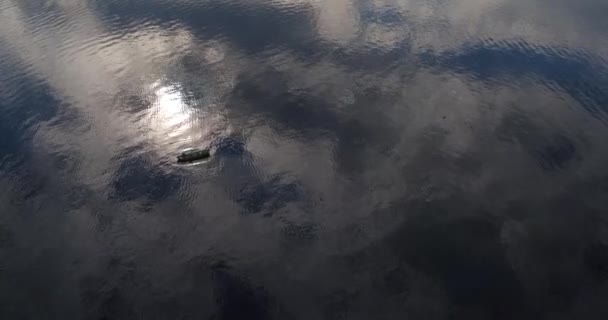 Silueta de canoa en la superficie del lago con reflejos de nubes — Vídeo de stock