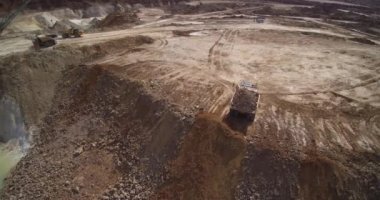 Çöp kamyonu, maden makinelerinin arasında büyük bir çukura boşaltıyor.