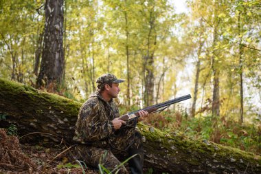 Sonbahar ormanın içinde silahlı bir avcı