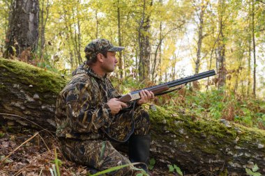 Sonbahar ormanın içinde silahlı bir avcı