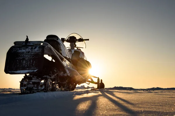 Een Sneeuwscooter Staat Sneeuw Bij Zonsondergang — Stockfoto