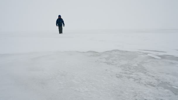 Uomo Cammina Una Superficie Ghiacciata Lago Inverno Una Tempesta Neve — Video Stock