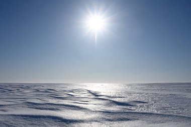 Güneşli bir kış gününde gölün donmuş yüzeyi.