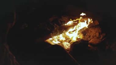 Bir grup arkadaş, gece deniz kenarındaki kumsalda kamp ateşinin yanında eğleniyorlar. Kamp ateşi, hızlı çekim, ağır çekim, 4k.