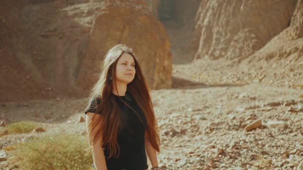 Toeristisch vrouwtje wandelen langs de rotsachtige canyon en maak foto 's in de hete woestijn. Desert canyon achtergrond, Egypte, Sinaï, slow motion, 4k — Stockvideo