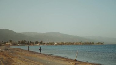 Küçük dalgalarla denizde iki balıkçı. Sahilden dönen bir adam, yavaş çekim..