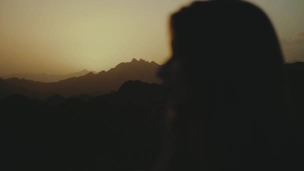 Gün batımında çölde yürüyen güzel genç bir kadının silueti. Çölde giden kadın, kum tepeleri, yakın çekim, yavaş çekim, 4k — Stok video