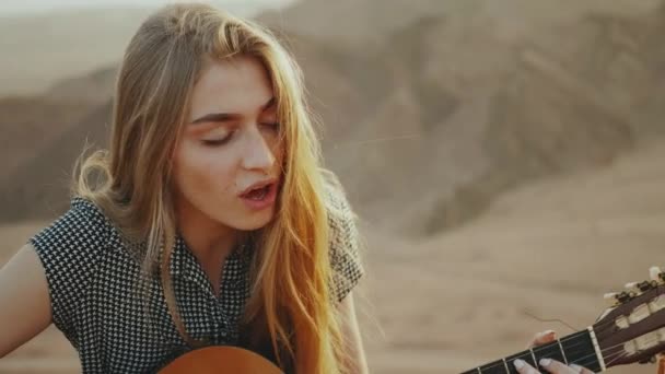 Femmina suonare la chitarra e cantare in paesaggi desertici, deserto montagne sfondo, slow motion, 4k — Video Stock