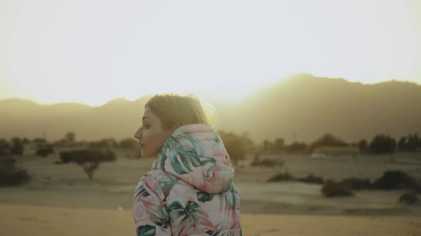 Mooie blonde vrouw lopen bij zonsondergang in de woestijn. Vrouw door de woestijn, duinen, close-up, slow motion, 4k — Stockvideo