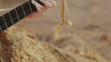 Gitar çalan ve çöl manzaralarında şarkı söyleyen kadın, çöl arkaplanı, ağır çekim, 4k