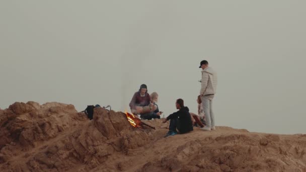 Grupo de amigos relaxando no topo de uma montanha ao pôr-do-sol, sentados perto da fogueira, desfrutando de seu tempo amizade, juventude, câmera lenta, 4k — Vídeo de Stock