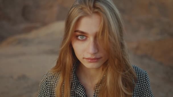 Portret van een mooie blonde vrouw bij zonsondergang. Gelukkige jonge vrouw staat in een woestijn bergen, zonsondergang landschap, slow motion, 4k — Stockvideo
