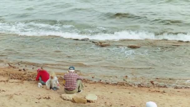 Grandfather with grandchildren playing on the beach by the sea, slow motion, 4k — Stock Video