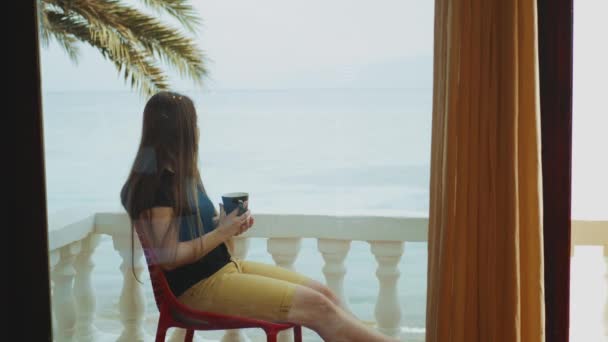 Ensam kvinna dricker kaffe eller te på morgonen på balkong med blå havsutsikt, synvinkel från fönstret, snabb video, slow motion, 4k — Stockvideo